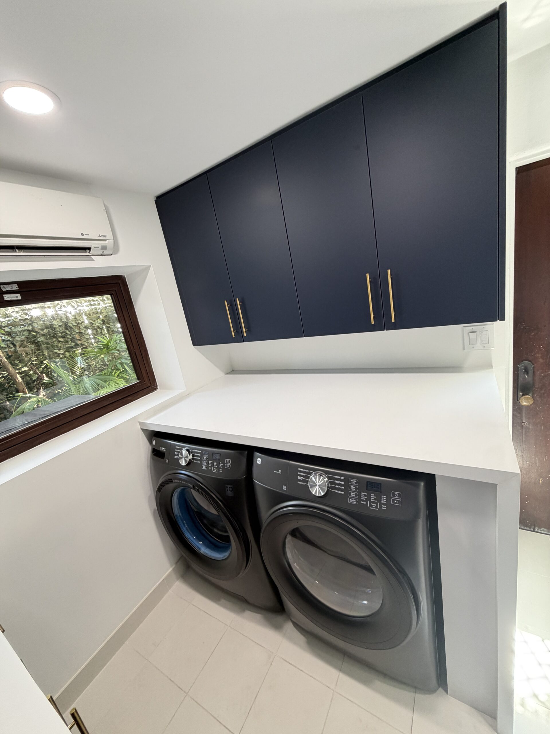 Concealed washer and dryer under custom cabinetry in remodeled laundry room